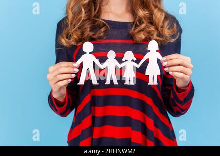 Donna sconosciuta che indossa un pullover casual a righe, donna che tiene carta catena di famiglia, relazioni tra bambini e genitori. Studio interno girato isolato su sfondo blu. Foto Stock