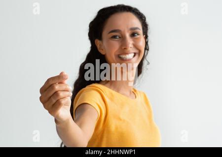 Happy Lady che tiene in mano un oggetto invisibile e lo mostra alla fotocamera Foto Stock