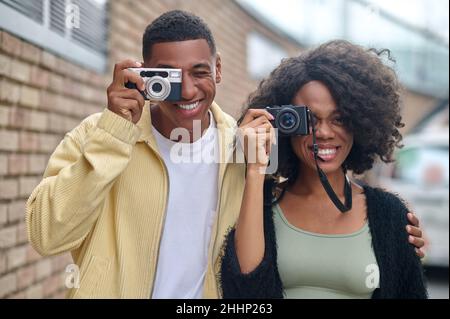 Uomo e donna che guardano attraverso l'obiettivo della fotocamera sulla strada Foto Stock