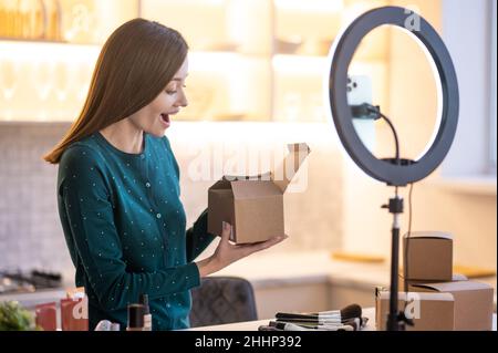 Giovane vettura sorridente di bellezza che presenta i nuovi prodotti di bellezza al pubblico in linea Foto Stock