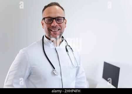 Primo piano ritratto di un medico maschio con uno stetoscopio intorno al collo e cappotto medico bianco Foto Stock