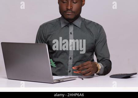 Giovane uomo d'affari nero che detiene naira e dollaro segno, lavorando con un portatile Foto Stock