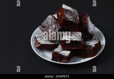 Pezzetti di torta al caffè cosparsi di zucchero a velo su un piatto di porcellana bianca Foto Stock