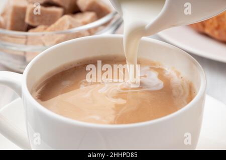 Versare il latte o la panna in un caffè appena fatto, primo piano Foto Stock