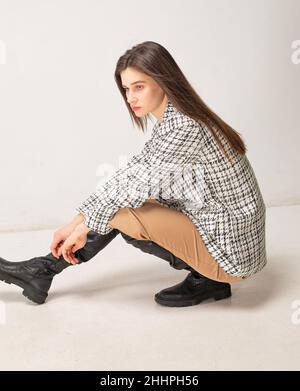 Squadrando giù giovane donna sottile con i capelli scuri isolati su beige chiaro Foto Stock