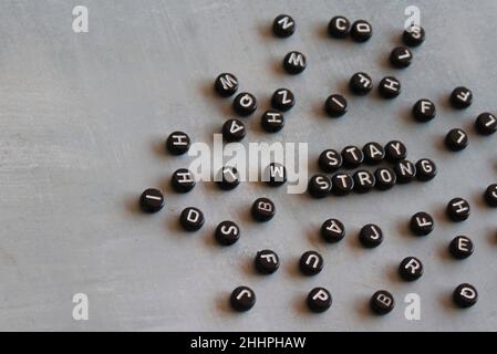 L'immagine di messa a fuoco selettiva delle perle dell'alfabeto con il testo RIMANE FORTE sul pavimento in cemento. Foto Stock
