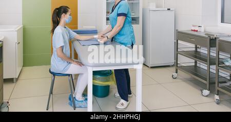 Un medico si è avvolto intorno al polso per primo soccorso. Applicazione di bende sulle mani del paziente, concetti di pronto soccorso e lesioni al polso Foto Stock