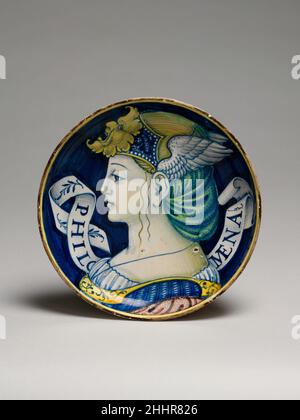 Piastra (una di una coppia) ca. 1525 o più tardi stile di Nicola da Urbino Italiano queste due ciotole calpestabili (vedi anche 65,6.7), o coppe, fanno parte di una delle più suggestive serie di maioliche prodotte nel 1520s. Sono stati fatti per un patrono non identificato e sono dipinti con busti di eroi illustri ed eroine, antichi e moderni. I caschi, nel loro stile classicizzante, sono paragonabili a quelli dei ritratti di monete antiche e delle medaglie contemporanee. Piastra (una di una coppia). Italiano, Castel Durante. Ca. 1525 o versione successiva. Maiolica (terracotta stagnata). Ceramica-ceramica Foto Stock