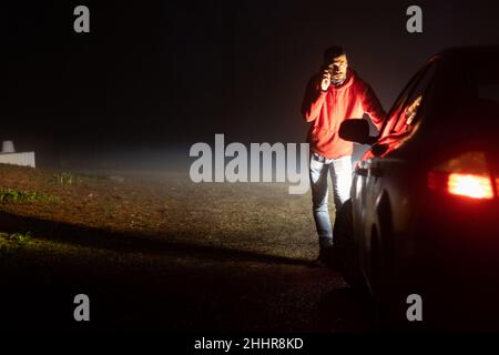 Uomo che chiama compagnia di assicurazione fuori della sua auto rotta Foto Stock