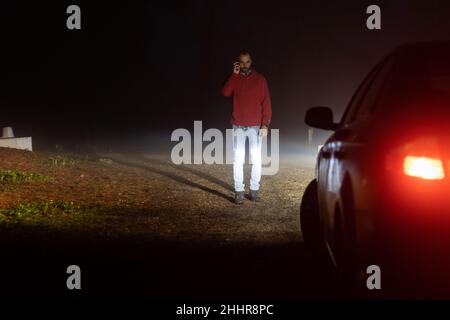 Uomo che chiama compagnia di assicurazione fuori della sua auto rotta Foto Stock