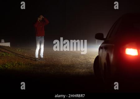 Uomo che chiama compagnia di assicurazione fuori della sua auto rotta Foto Stock