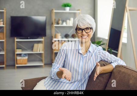 Responsabile aziendale femminile maturo seduto di fronte a una webcam e incontro online con i suoi clienti. Foto Stock