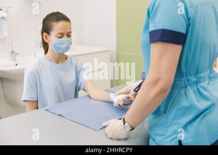 Un medico si è avvolto intorno al polso per primo soccorso. Applicazione di bende sulle mani del paziente, concetti di pronto soccorso e lesioni al polso Foto Stock