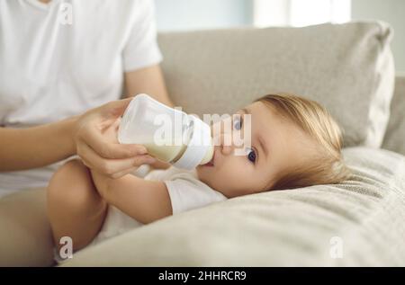 Adorabile bambino ragazzo o ragazza bere latte nutriente formula da bottiglia che la madre dà Foto Stock