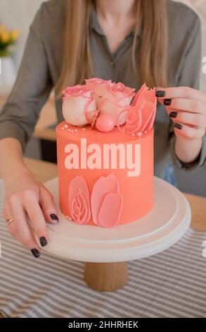 torta rosa con rose e petali su un supporto , un pezzo di torta Foto Stock