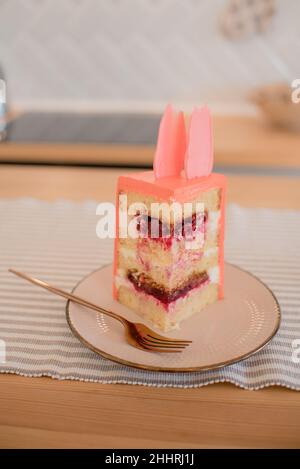 torta rosa con rose e petali su un supporto , un pezzo di torta Foto Stock