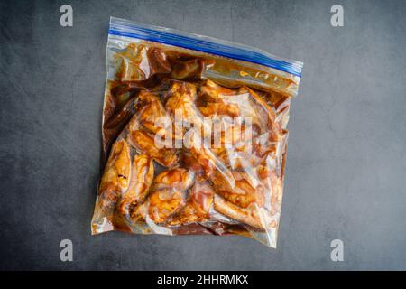 Ali di pollo crude marinate in un sacchetto di plastica: Ali di pollo crude e marinate in un sacchetto con chiusura lampo Foto Stock