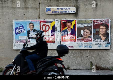 Marsiglia, Francia. 25th Jan 2022. Un uomo su uno scooter passa davanti ai manifesti di Jean-Luc Mélenchon (L), Fabien Roussel (C) e Nathalie Arthaud (R) in mostra.Posters campagna di Nathalie Arthaud, Fabien Roussel, Philippe Poutou e Jean-Luc Mélenchon, candidati per le elezioni presidenziali francesi del 2022. Credit: SOPA Images Limited/Alamy Live News Foto Stock