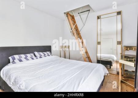 Moderna camera da letto con le scale di accesso alla mansarda superiore Foto Stock