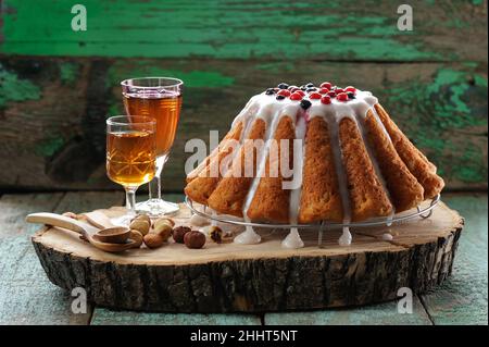 Gugelhupf con bicchieri, cucchiai di legno e noci su corteccia di legno orizzontale Foto Stock