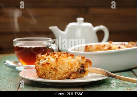 Budino di Panettone e tè nero caldo a vapore su sfondo di legno shabby primo piano Foto Stock