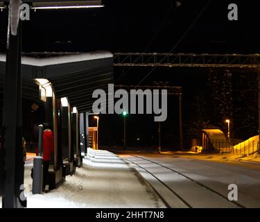 Piattaforma ferroviaria coperta di neve di notte. Estonia Lockal stazione ferroviaria. Foto Stock
