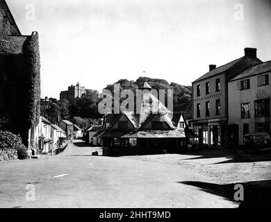 Una gemma di antichità rustica, la bellissima Dunster, Somerset, fu metà dimenticata quando il motorista posò la sua auto durante gli anni della guerra. Ma presto questo angolo incontaminato dell'Inghilterra accoglierà nuovamente i turisti. Nella foto, il mercato dei filati con il castello di Dunster sullo sfondo nella strada principale ancora deserta. 25th giugno 1945. Foto Stock