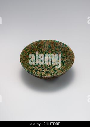 Glass Bowl in Millefiori tecnica 9th secolo la tecnica millefiori fu riscoperta nell'VIII o nono secolo in Mesopotamia e fu probabilmente utilizzata nella produzione di oggetti per i calibri Abbasidi a Baghdad o Samarra. Un certo numero di ciotole e di mattonelle superstite suggeriscono che è stato usato sia per l'arredamento domestico che per la decorazione interna. Esempi come questi mostrano la sofisticazione e la gamma dei vetrai Abbasid. Ciotola di vetro in tecnica Millefiori. 9th secolo. Vetro, verde, giallo opaco e mosaico rosso opaco; fuso, intaccato, rettificato e lucidato, piede applicato. Prodotto in Proba Foto Stock