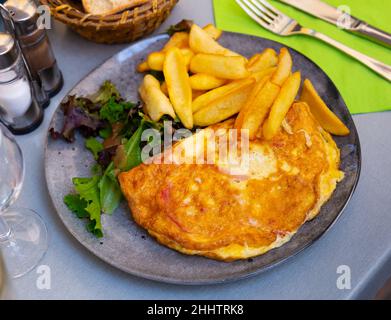 Porzione di omelette gourmet con patate fritte Foto Stock