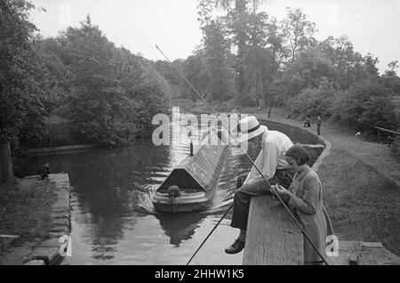 Un giovane pescatore che indossa un cappello di panama che pesca nel Canal Grande Union tra Rickmansworth e Watford, mentre il suo giovane compagno bagna la sua canna Circa 1950 Foto Stock