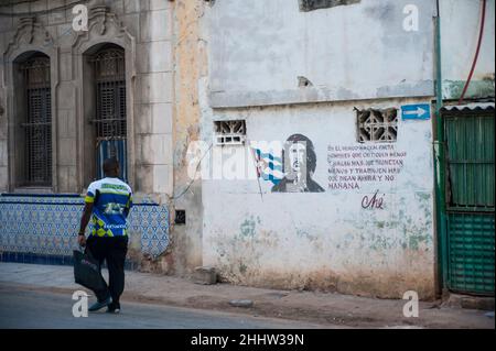 Citazione dal leader della Rivoluzione Cubana che Guevara mentre un uomo cammina oltre tenendo una borsa. Foto Stock