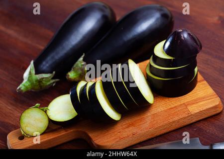 Melanzane fresche affettate su una scrivania in legno in cucina Foto Stock