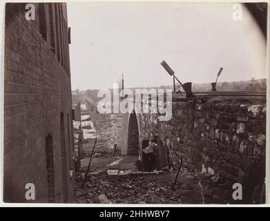 Rovine di Richmond & Petersburg Railroad Bridge, Richmond, Virginia ca. 1865 Alexander Gardner American, lo scozzese Alexander Gardner, John Reekie e altri membri del corpo di fotografi di Gardner furono i primi a documentare Richmond, Virginia, dopo la sua evacuazione da parte del governo confederato il 2 aprile 1865. Gardner non era stato sul campo con le sue macchine fotografiche da quando ha lasciato Gettysburg nel luglio 1863. Arrivò a Richmond il 6 aprile e lavorò per cinque giorni producendo decine di viste stereo e di grande formato dei ponti distrutti attraverso il fiume James e nei venti blocchi quadrati del Foto Stock