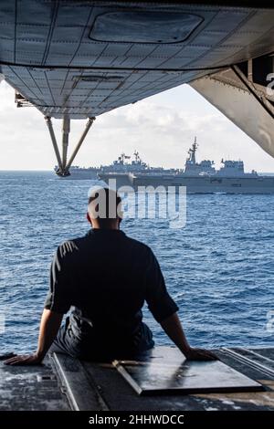 MAR DELLE FILIPPINE (ago. 22, 2022) CPL. Austin Totton, di Lake City, Michigan, assegnato alla Marine Expeditionary Unit del 31st, osserva la nave della forza di autodifesa marittima giapponese JS Hyuga (DDDH 181), Right, e la nave d'assalto anfibio di classe Wasp USS Essex (LHD 2) in formazione con la nave d'assalto anfibio dispiegata in avanti USS America (LHA 6). Operando come parte della U.S. Pacific Fleet, Essex e America, insieme a JS Hyuga, stanno conducendo corsi di formazione per preservare e proteggere una regione indopacifica libera e aperta. (STATI UNITI Foto Navy di Mass Communication Specialist 3rd Classe Thomas Contant) Foto Stock
