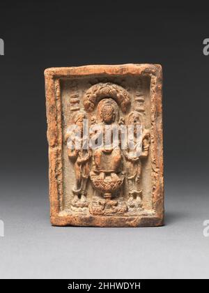 Buddha seduto fiancheggiato da due Bodhisattvas 7th–9th Thailandia del secolo Un gran numero di placche in stile Mon del settimo al nono secolo, ricche di varianti iconografiche, sono sopravvissute dalla Thailandia. Queste placche votive in terracotta, realizzate in stampo, devono essere comunemente disponibili nei principali luoghi di pellegrinaggio buddista e nei centri religiosi più importanti. La loro ampia disponibilità e la loro facile portabilità contribuirono a diffondere la dottrina, gli stili e l'iconografia buddisti in tutto il Sud e Sud-Est asiatico, così come nell'Estremo Oriente. Buddha seduto fiancheggiato da due Bodhisattvas 64117 Foto Stock