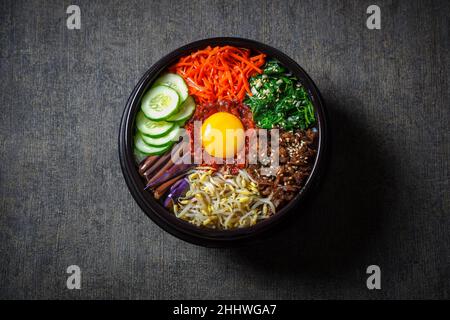 Piatto di riso in stile coreano Bibimbap. Ciotola di riso bianco caldo con bubuggi di manzo, verdure saltate e condite Foto Stock
