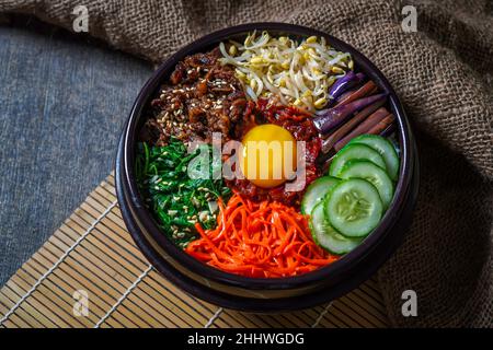 Piatto di riso in stile coreano Bibimbap. Ciotola di riso bianco caldo con bubuggi di manzo, verdure saltate e condite Foto Stock