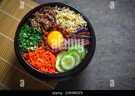 Piatto di riso in stile coreano Bibimbap. Ciotola di riso bianco caldo con bubuggi di manzo, verdure saltate e condite Foto Stock