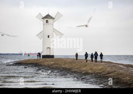 Swinoujscie, Polonia. 17th Nov 2021. La gente ha visto camminare intorno al faro di Stawa Mlyny, situato all'ingresso del porto di Swinoujscie. Un faro bianco a forma di mulino a vento è un simbolo di Swinoujscie ed è parte del logo ufficiale della città. Il Porto di Swinoujscie è un porto marittimo polacco sul Mar Baltico. Insieme al porto di Szczecin, crea uno dei più grandi complessi portuali del Mar Baltico. (Foto di Karol Serewis/SOPA Images/Sipa USA) Credit: Sipa USA/Alamy Live News Foto Stock