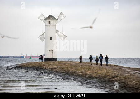 Swinoujscie, Polonia. 17th Nov 2021. La gente ha visto camminare intorno al faro di Stawa Mlyny, situato all'entrata del porto di Swinoujscie.Un faro bianco nella forma di un mulino a vento è un simbolo di Swinoujscie ed è una parte del logo ufficiale della città. Il Porto di Swinoujscie è un porto marittimo polacco sul Mar Baltico. Insieme al porto di Szczecin, crea uno dei più grandi complessi portuali del Mar Baltico. (Credit Image: © Karol Serewis/SOPA Images via ZUMA Press Wire) Foto Stock