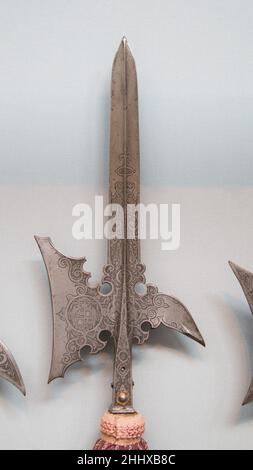 Halberd di Wolf Dietrich von Raitenau, principe-arcivescovo di Salisburgo (regnò 1587–1612) datato 1589 tedesco questo halberd, con la sua lama leggermente concava di ascia, ampia punta apicale con cresta intermedia affilata, becco fortemente curvo, E fantasiosamente scrollata, è tipico delle armi da sfilata utilizzate dalle guardie del palazzo dei principi tedeschi durante la seconda metà del XVI secolo e per tutto il XVII secolo. Tutta la sua superficie, compresa la bussola quadrata e le lunghe cinghie in acciaio (Schaftfedern) che fissano la testa al gambo, è fortemente incisa con grollwork e grottesche. Su uno dei due Foto Stock