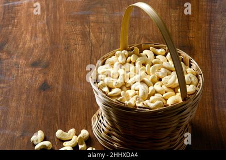 Arachide crude arrosto salate in una ciotola di legno su un tavolo rustico, sano spuntino vegetariano, anacardium occidentale, anachide su sfondo bianco, anachide. Foto Stock