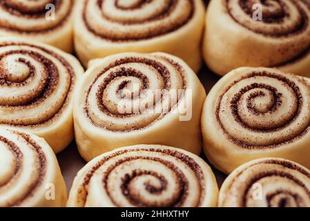 Dolci alla cannella cruda o cinnabon da vicino, dolci alla cannella cruda pronti per la cottura. Dolci panini da dessert tradizionali Foto Stock