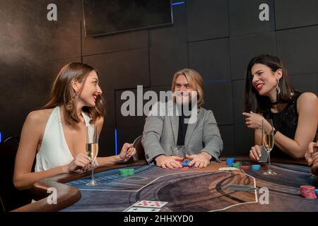 Uomo allegro che raccoglie chip dopo il gioco di poker di successo al tavolo Foto Stock