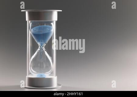 La sabbia blu che scorre attraverso bulbi di clessidra misura il tempo di passaggio nel conto alla rovescia Foto Stock