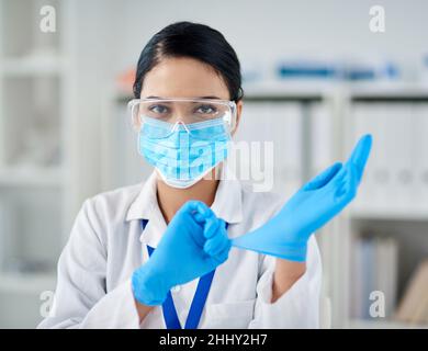 Prepariamoci alla scienza. Ritratto di una giovane donna sicura indossando guanti chirurgici in laboratorio. Foto Stock