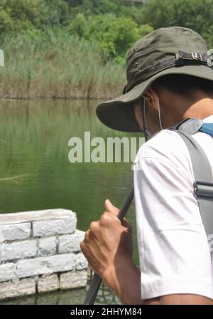 Vista posteriore di un turista maschile che cammina all'aperto accanto al lago con spazio copia Foto Stock