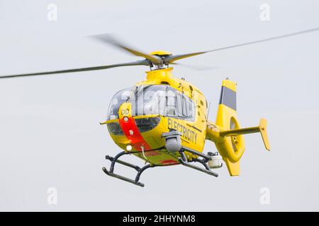 Elicottero giallo WPD (utilizzato nell'industria della distribuzione di energia elettrica per la manutenzione/riparazione della rete e l'ispezione della linea elettrica) che vola isolato in cielo. Foto Stock