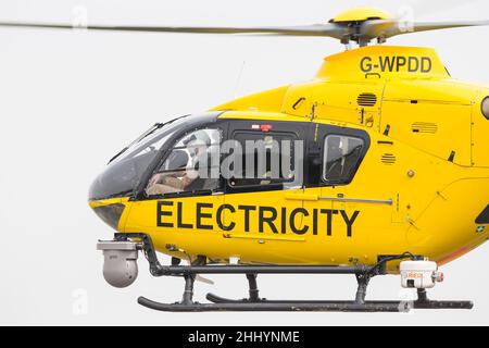 Elicottero giallo WPD (utilizzato nell'industria della distribuzione di energia elettrica per manutenzione/riparazione/ispezione della linea elettrica) che vola isolato in cielo. Foto Stock