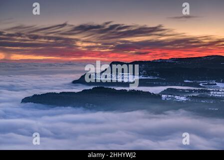 Altopiano di Capolat e montagne Les Tres Maries in un tramonto d'inverno con un mare di nuvole sulla regione centrale della Catalogna (Catalogna, Spagna) Foto Stock